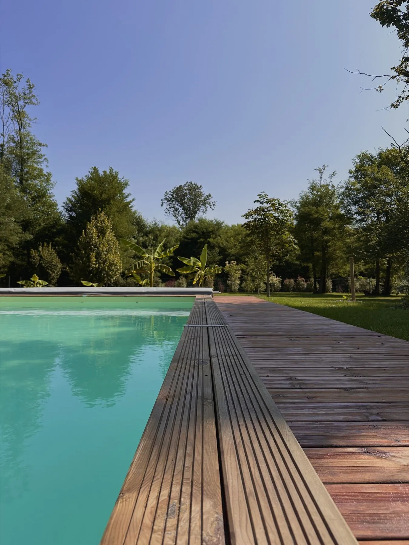 Milasson — vue en longueur de la piscine bordée de bois, Atelier Nola